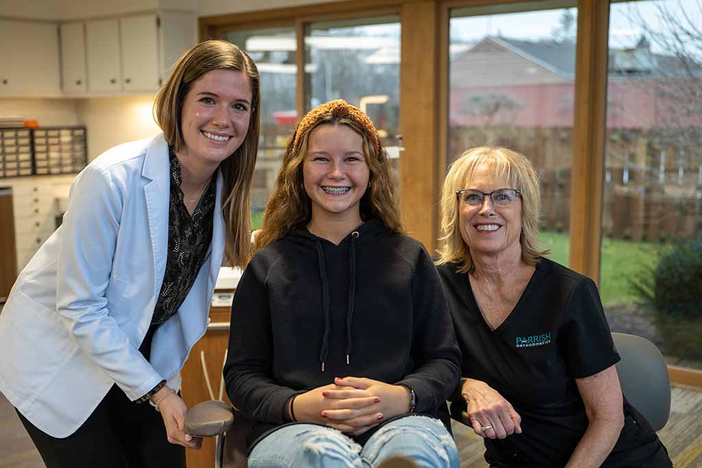 Orthodontist Dr. Kate Welch standing next to a female teenage patient with braces and a staff member in Fort Wayne